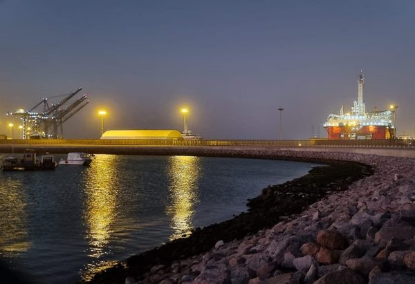 The harbour wall at night with a lit offshore rig