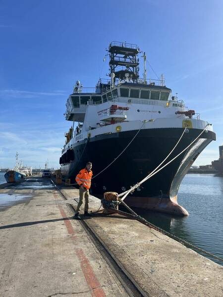 A salvage vessel alongside the quay with a technician in hi-vis
